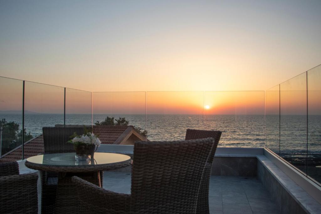 een tafel en stoelen op een balkon met een zonsondergang bij Agia Marina Chrysochous in Kato Yialia