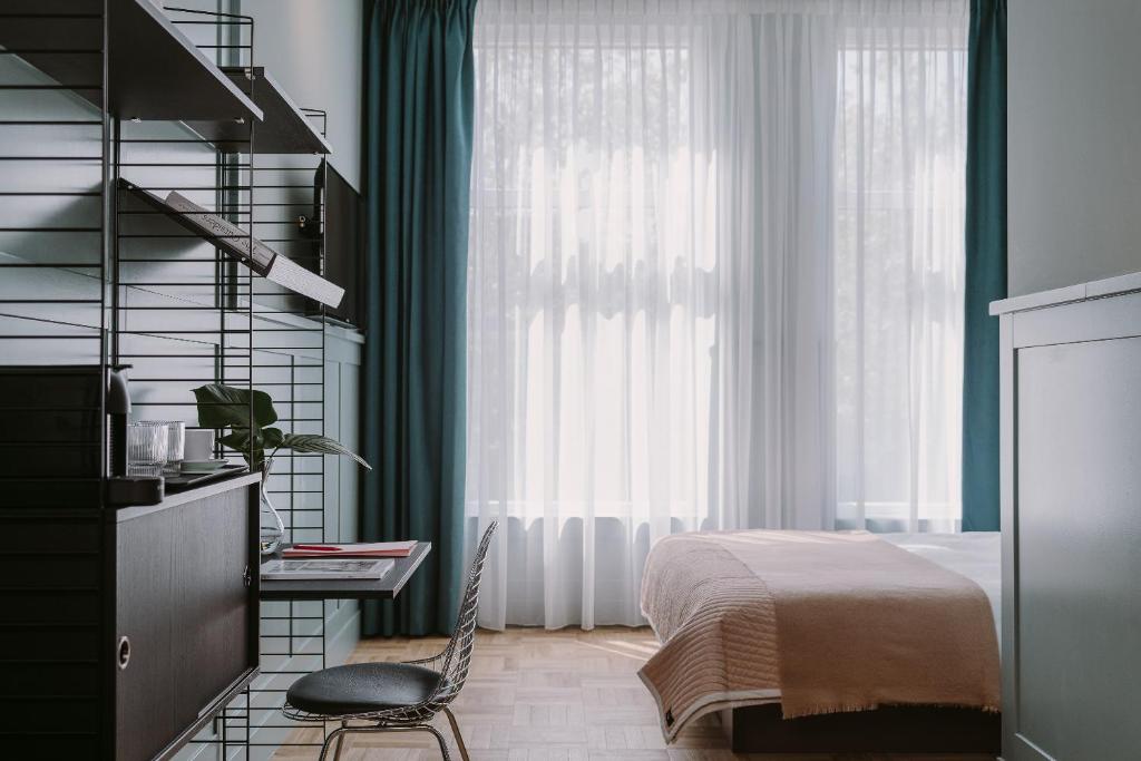 a bedroom with a bed and a desk and a window at Supernova Hotel in Rotterdam