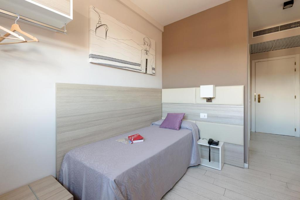 a bedroom with a bed with a purple pillow on it at Hotel Cristina in Naples