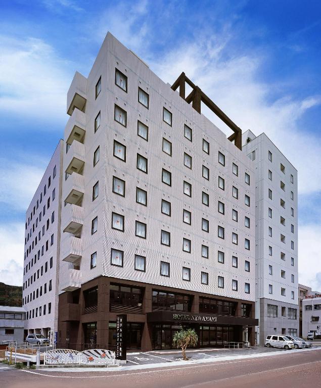 ein großes weißes Gebäude an einer Straßenseite in der Unterkunft Hotel New Amami in Amami