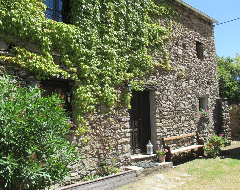 un edificio de piedra con un banco delante en Sole e Ventu 30qm, en San-Giovanni-di-Moriani