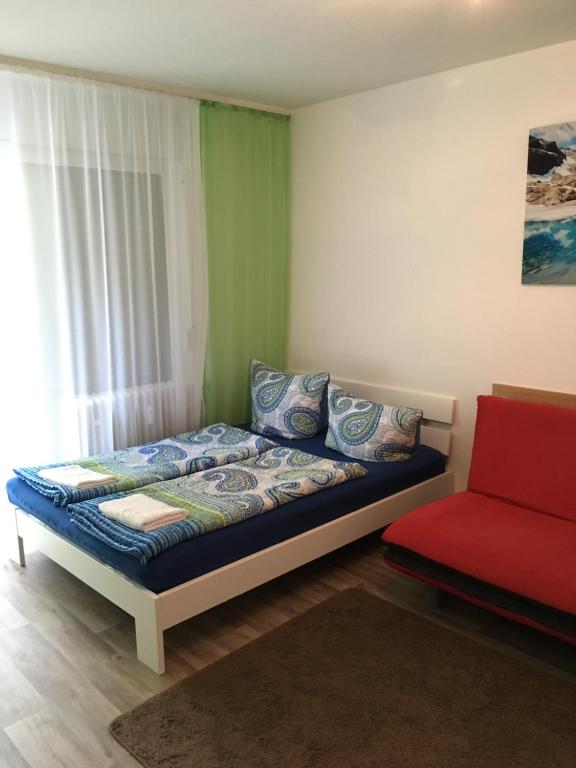 1 dormitorio con 1 cama y 1 sofá rojo en Apartment Schwarzwald, en Lahr
