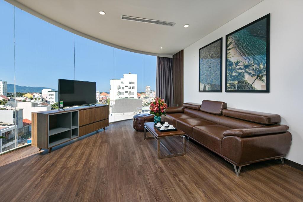 uma sala de estar com um sofá de couro castanho e uma televisão em Meliora Hotel & Apartment em Da Nang