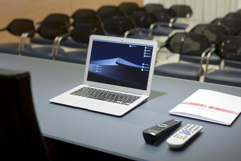 a laptop computer sitting on a table with a remote control at Hotel Cristina in Naples