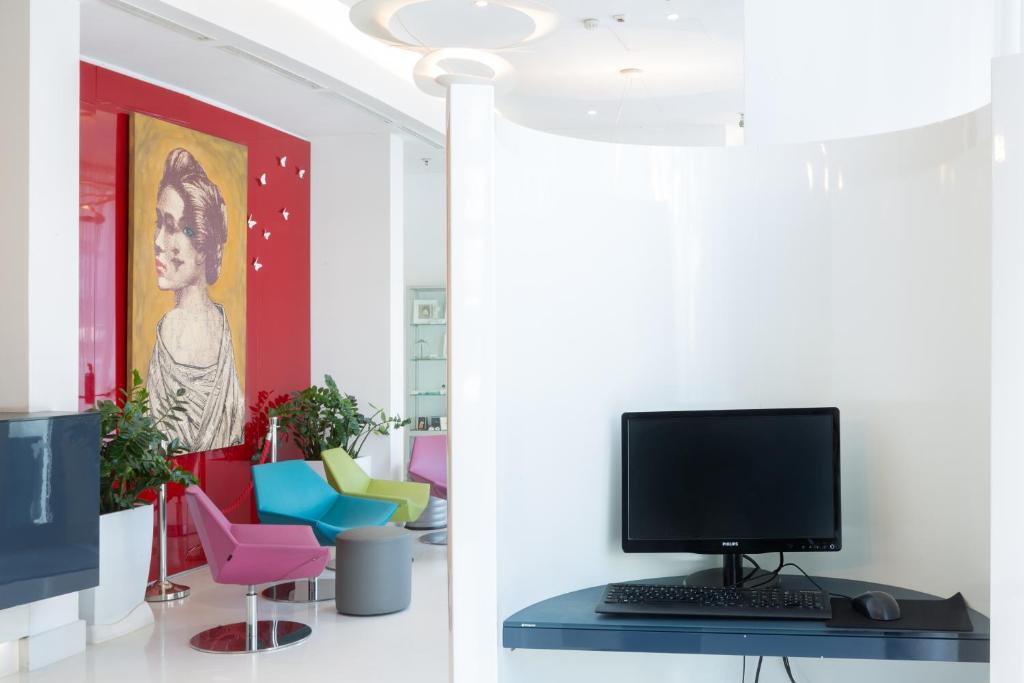 a computer on a desk in a room with colorful chairs at Hotel Cristina in Naples
