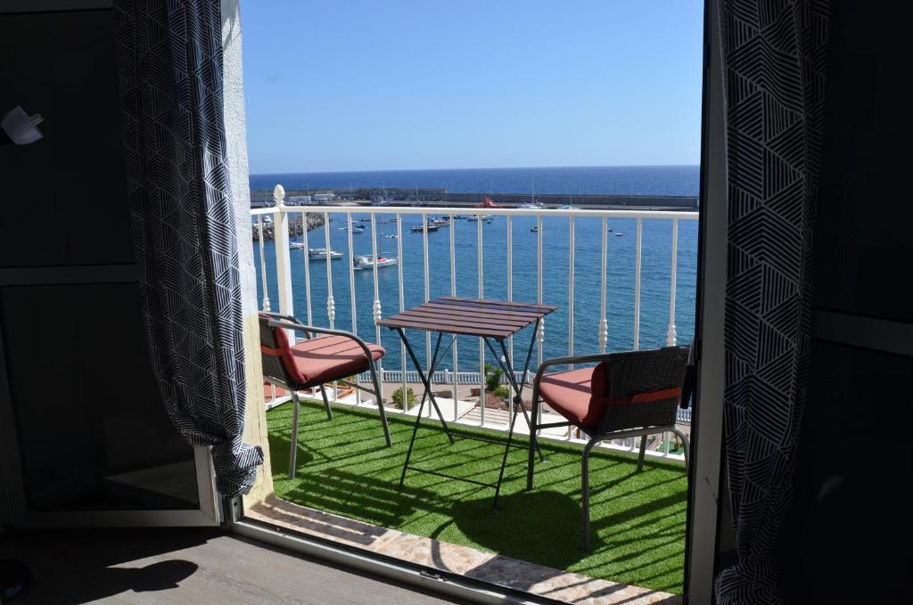 una ventana con vistas al agua, mesa y sillas en Vista Puerto Arguineguín Deporte y Relax, en La Playa de Arguineguín