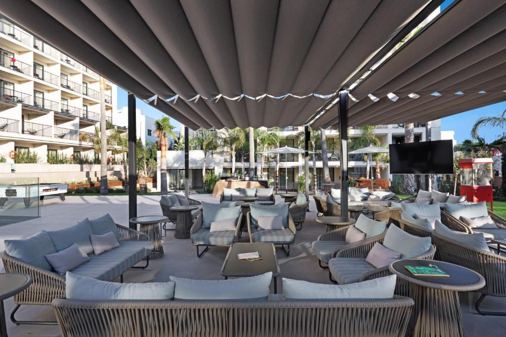 a patio with couches and tables and a television at Hotel Paradiso Garden in Playa de Palma