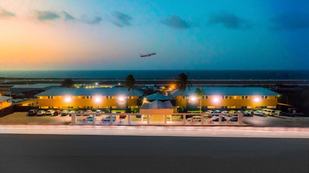 Curacao Airport Hotel في فيليمستاد: طائرة تطير فوق المطار ليلا