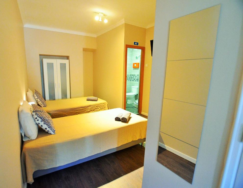 a small room with two beds and a mirror at Rooms DP Setúbal in Setúbal