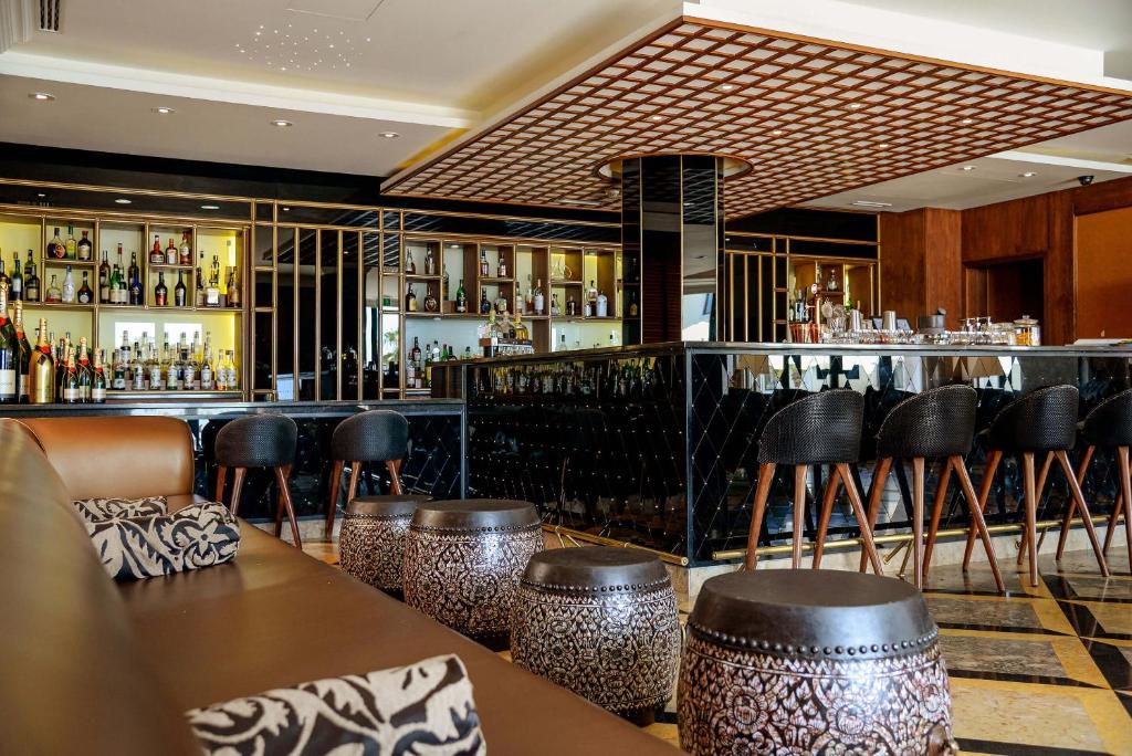a bar with leather stools and a bar counter at Grande Real Villa Itália Hotel & Spa in Cascais