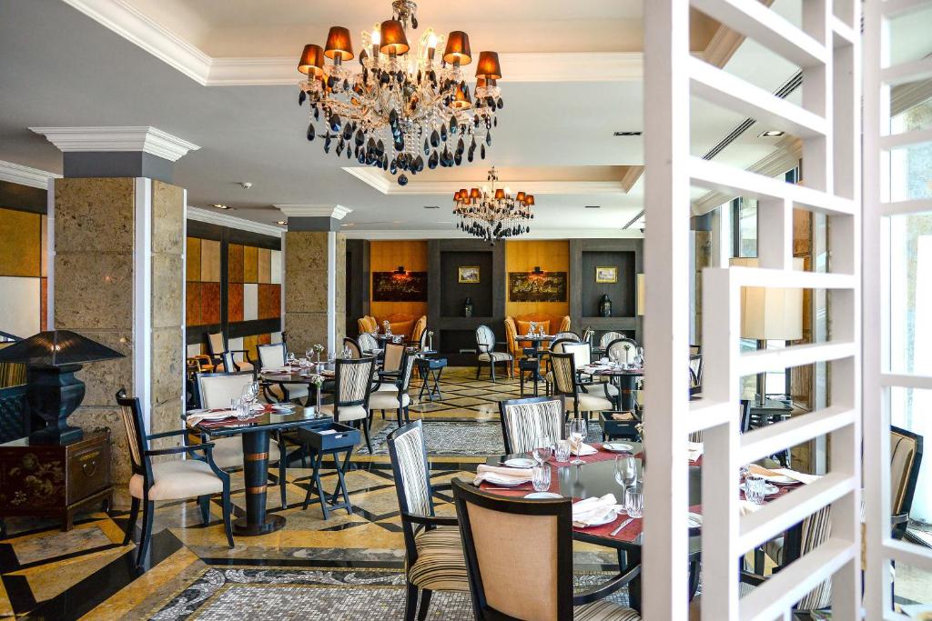 a dining room with tables and chairs and a chandelier at Grande Real Villa Itália Hotel & Spa in Cascais