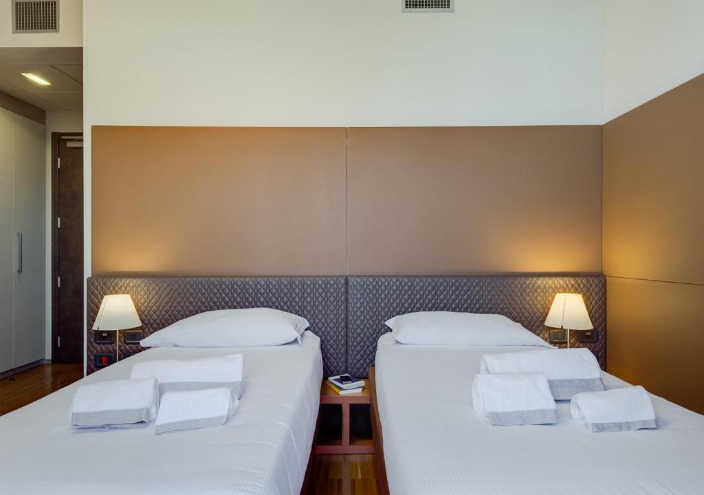 a hotel room with two beds and two lamps at Camplus Guest Bononia Casa per Ferie in Bologna