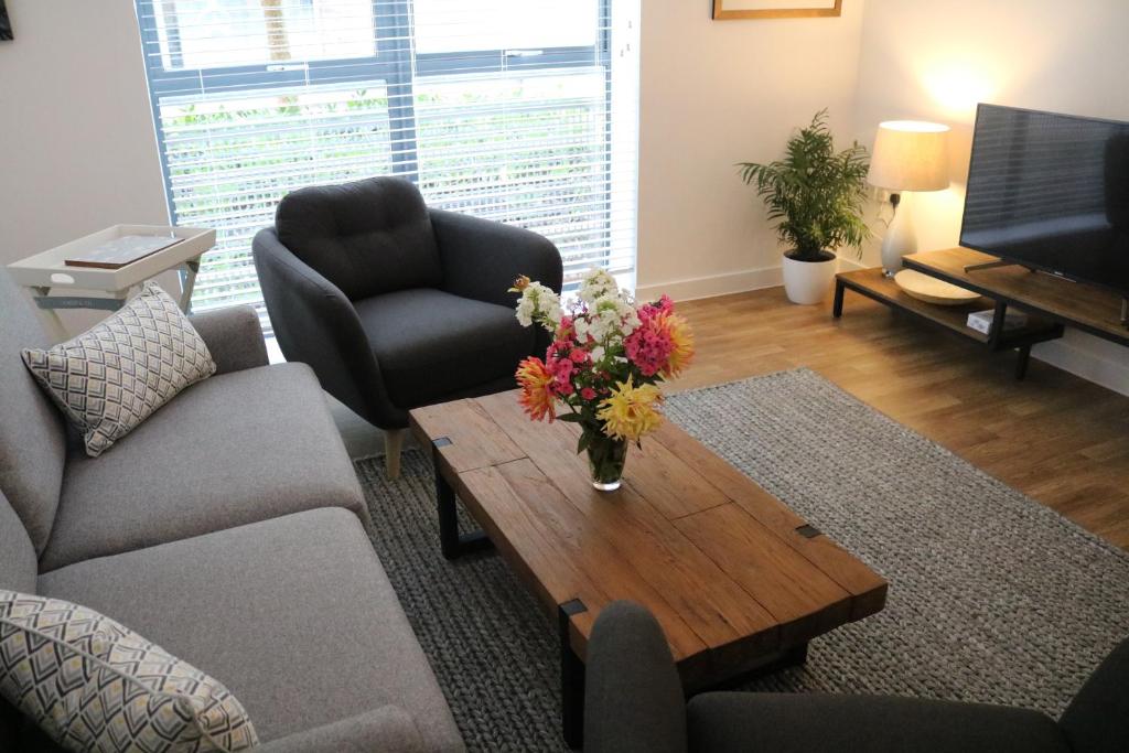 uma sala de estar com um vaso de flores numa mesa de centro em City Apartment em Winchester