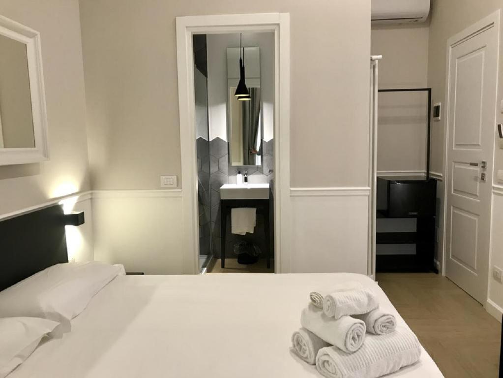 a bedroom with a white bed with towels on it at KUKKA ROOMS in Naples