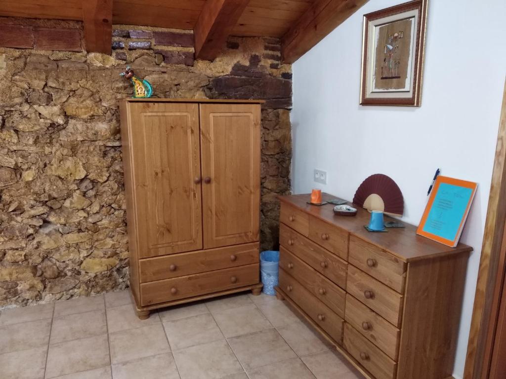1 dormitorio con armario de madera y pared de piedra en CA TONI, en Darmós