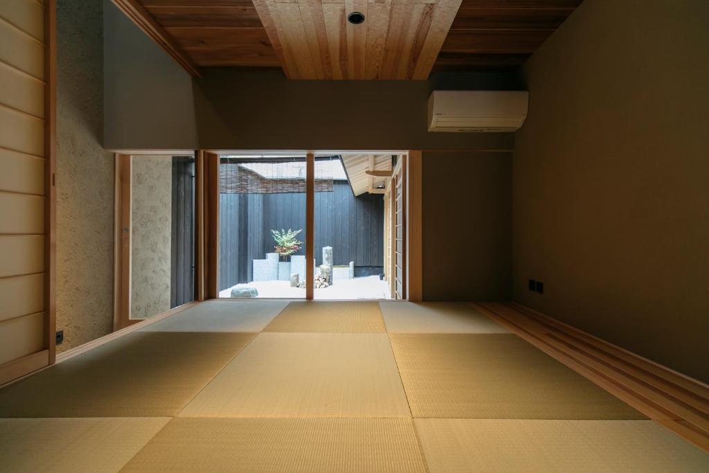 an empty room with a large window and wooden ceilings at MACHIYADO 京都南禅寺道 in Kyoto