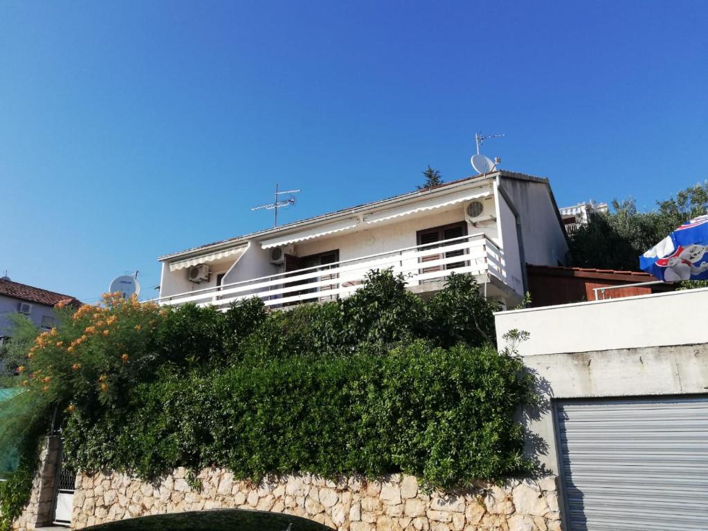 una casa blanca con una pared de piedra y arbustos en Apartment Gordana, en Trogir