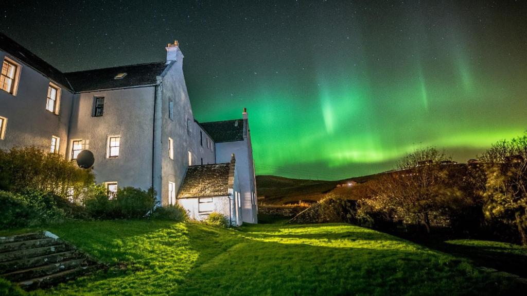 ein Bild der Aurora, die am Himmel neben einem Gebäude tanzt in der Unterkunft Busta House Hotel in Busta