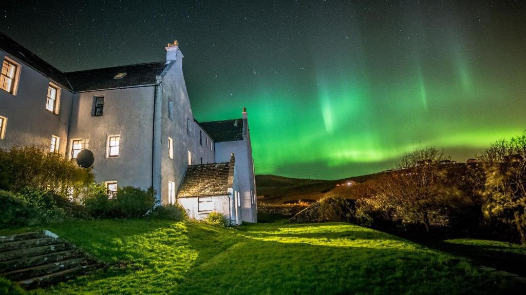 an image of the aurora dancing in the sky next to a building at Busta House Hotel in Busta