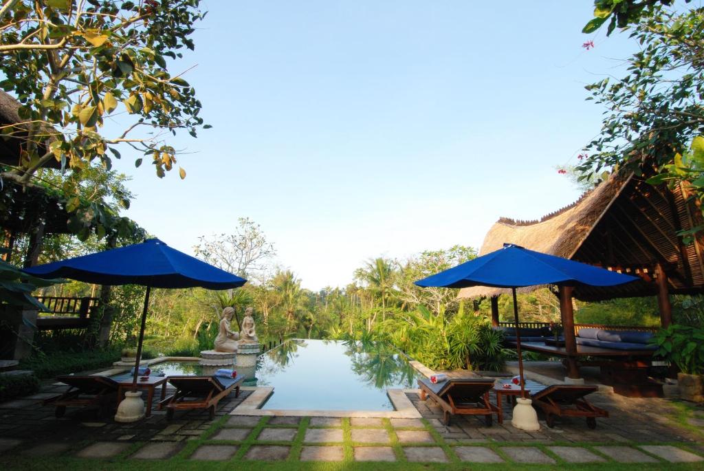 a resort with tables and umbrellas next to a pond at Villa Sebali in Ubud