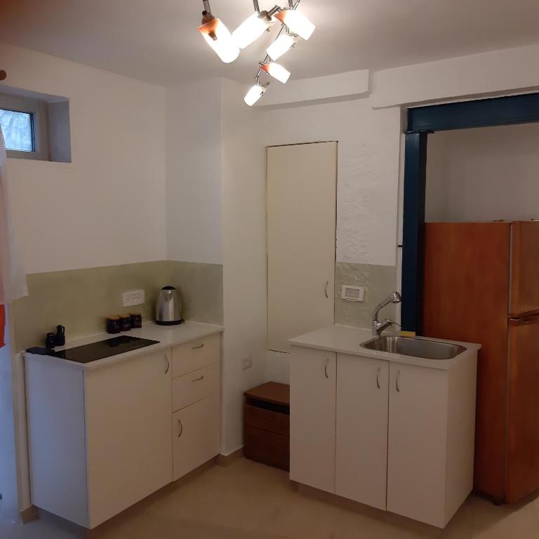 uma cozinha com armários brancos e um lavatório em Wild Rose em Jerusalém