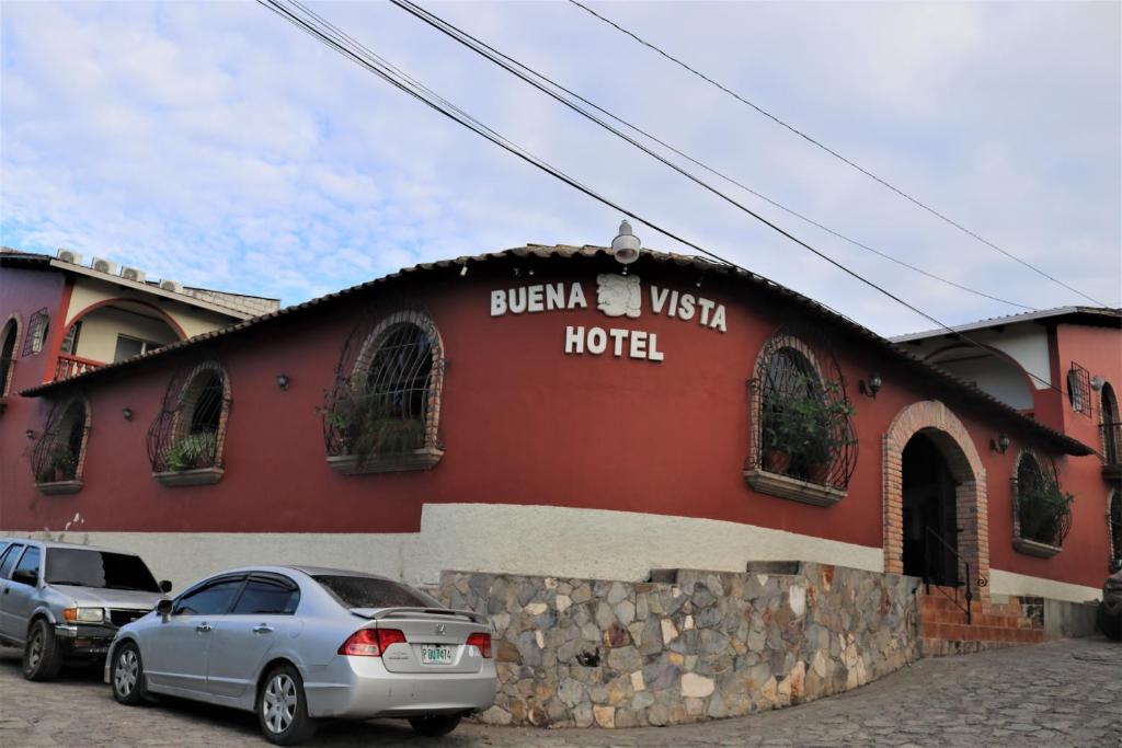 a red building with two cars parked in front of it at Hotel Buena Vista in Copán Ruinas
