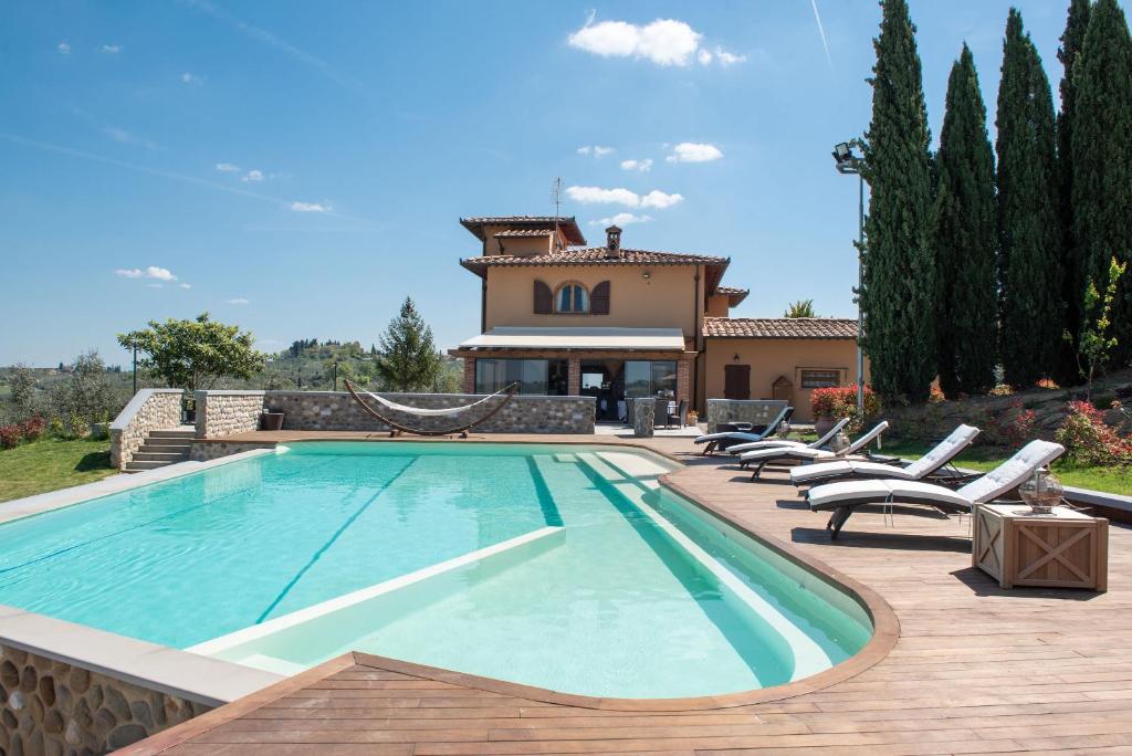 a swimming pool with chairs and a house at Agriturismo Casale Ugolini in Montespertoli