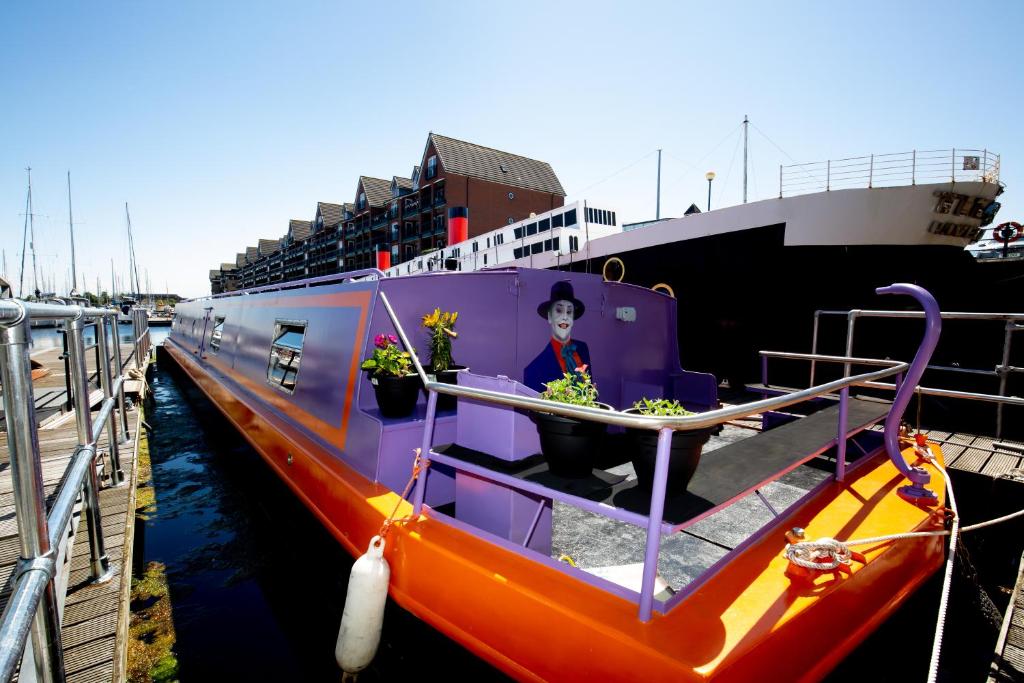 een oranje en paarse boot is aangemeerd naast een schip bij The Joker Boat in Liverpool