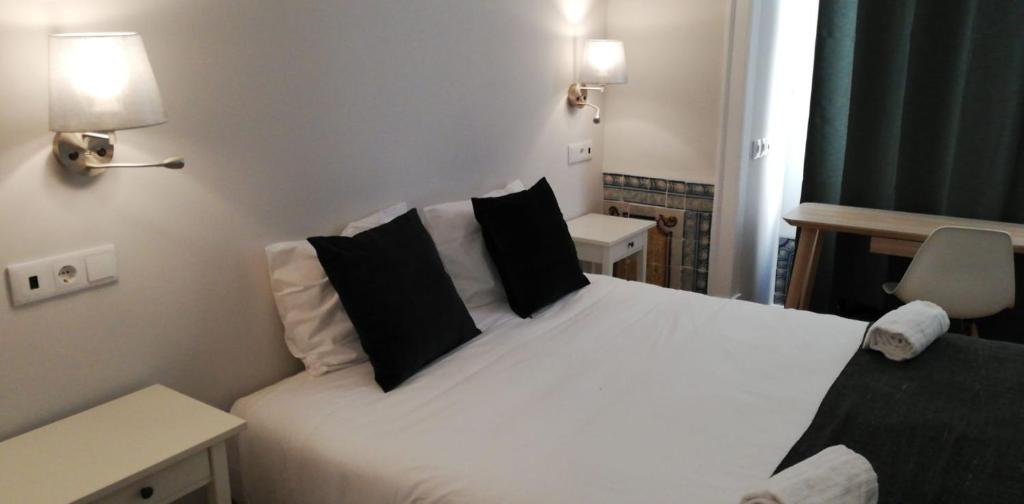 1 dormitorio con 1 cama blanca y 2 almohadas negras en Great Stay Fanqueiros 1, en Lisboa
