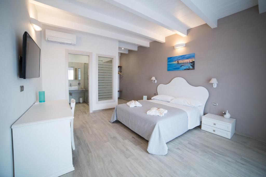 a white bedroom with a white bed and a tv at La seconda Luna in Pollutri