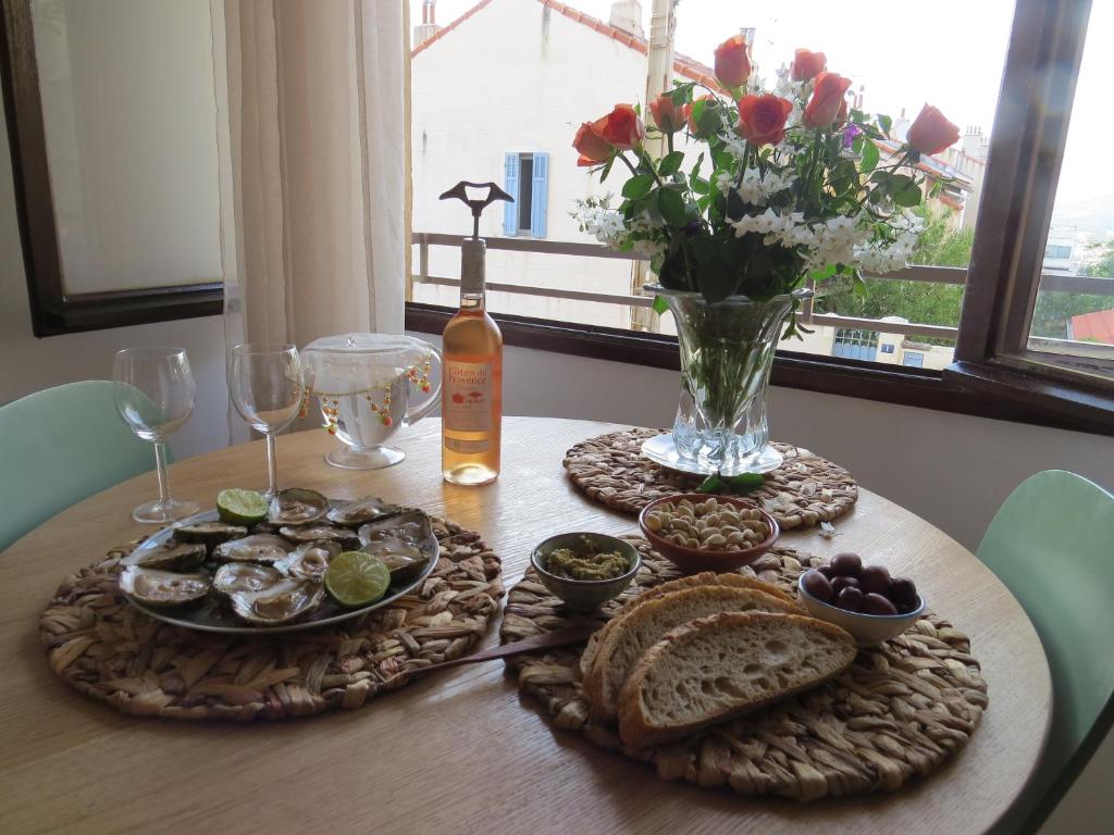 a table with plates of food and a vase of flowers at Studio calme et très lumineux, au pied de notre Dame de la Garde in Marseille