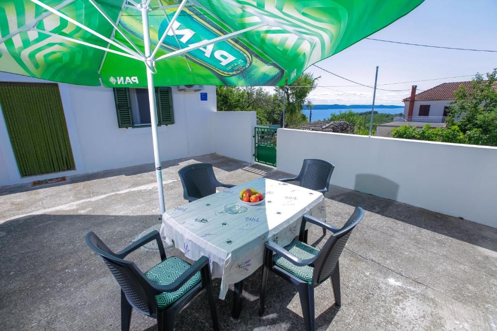 une table et des chaises sous un parasol vert dans l'établissement Holiday Home Nikola, à Savar