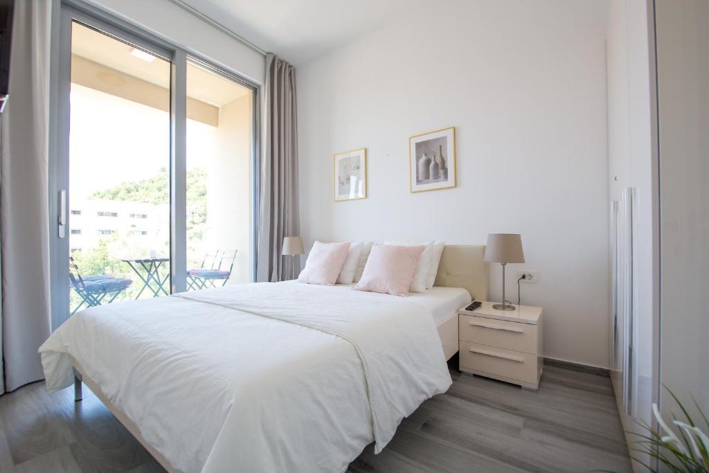 een witte slaapkamer met een groot bed en een raam bij Apart SKY Residence with sea view in DELMAR in Budva
