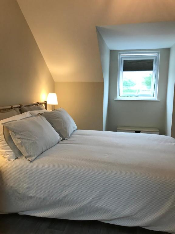 a bedroom with a large white bed with a window at Bush House Accommodation - The Distillery in Bushmills