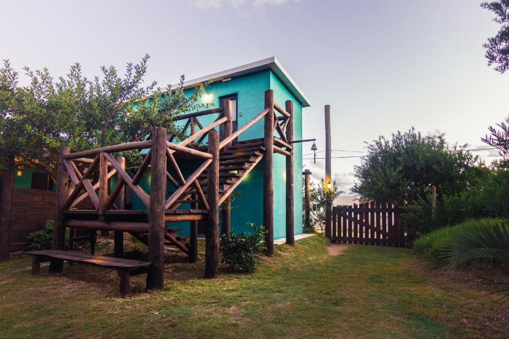 a green house with a bench in front of it at La Brújula Hostel in La Paloma