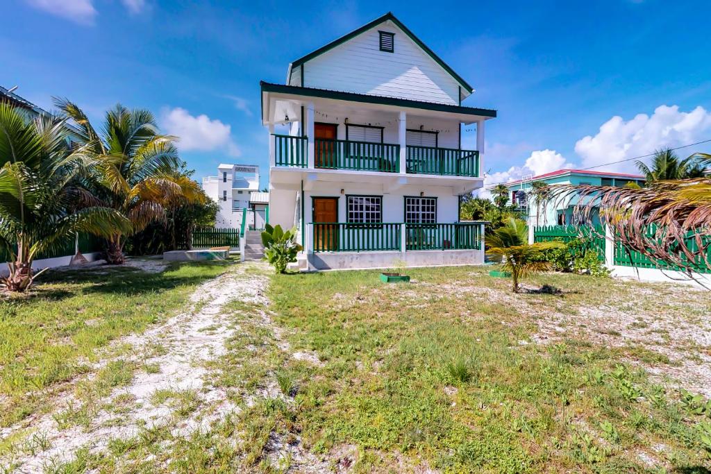 a white house on the beach with palm trees at Roughrider Inn in Caye Caulker