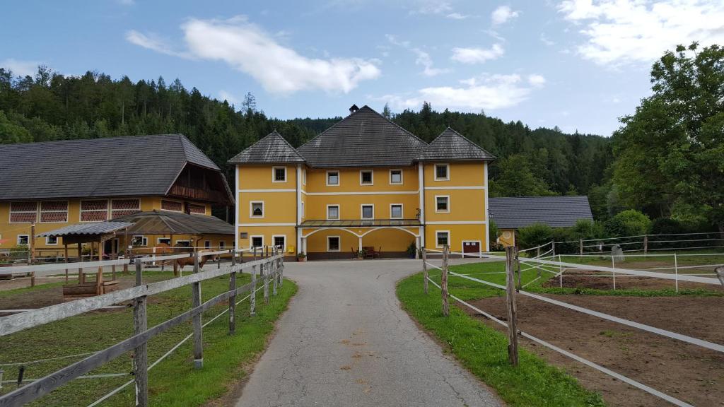 ein großes gelbes Gebäude mit einem Zaun. in der Unterkunft Ferienwohnungen Gut Seebacher in Klagenfurt am Wörthersee