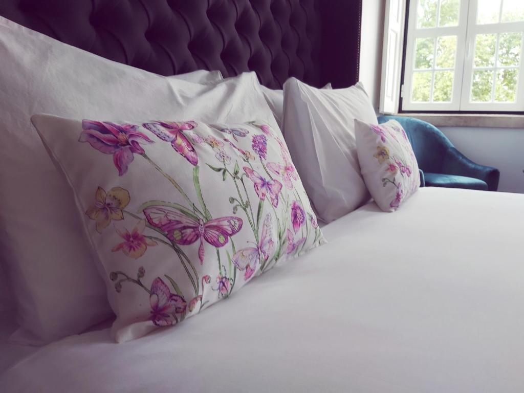 シントラにあるシントラ 1012 ブティック ゲストハウスのピンクの花が飾られた白い枕付きのベッド