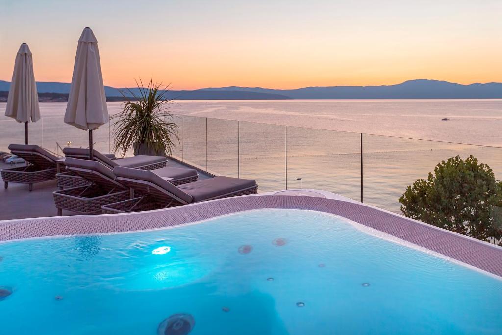 a swimming pool with chairs and a view of the ocean at Luxury Hotel Riva in Malinska