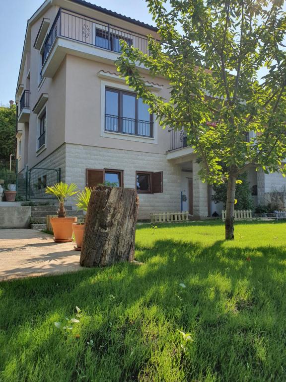 a house with a tree stump in front of it at Studio Apartman Marti in Kostrena