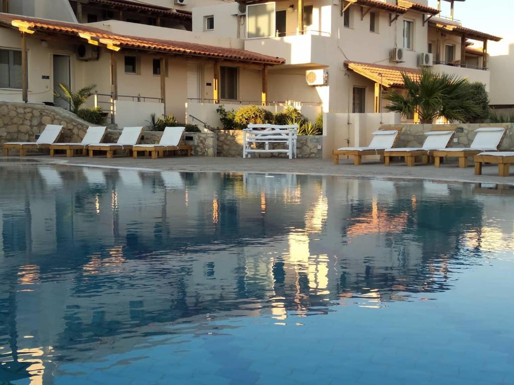 una piscina frente a un hotel con sillas y un edificio en Creta Suites, en Koutsounari