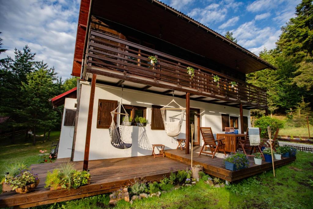 une maison avec une terrasse en bois dans la cour dans l'établissement Chata Pod Lasem, à Poręba