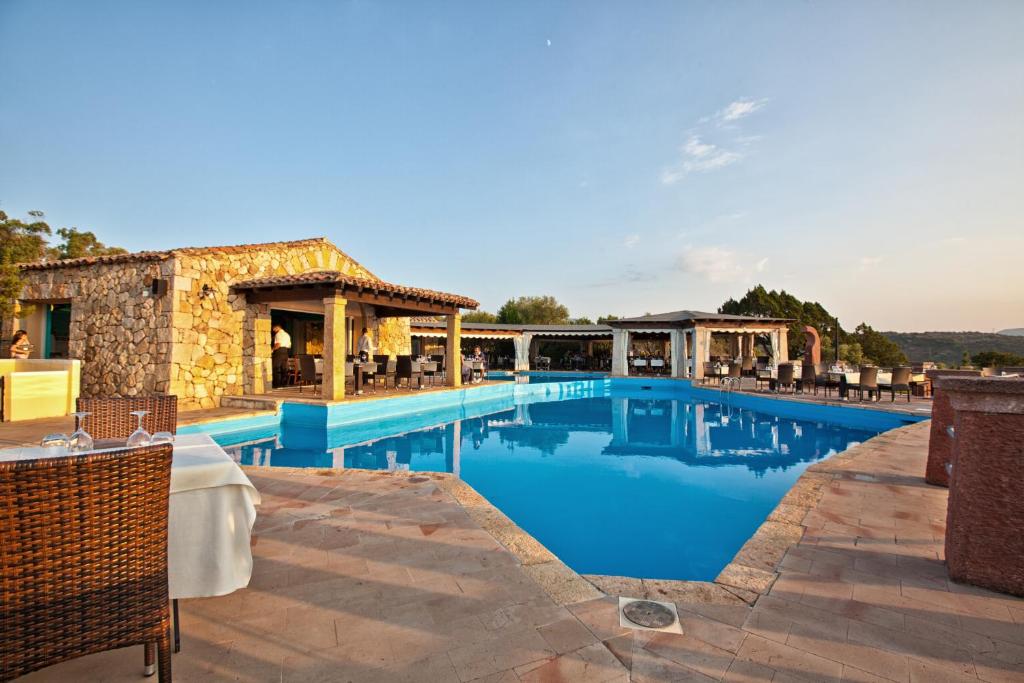 una piscina en un complejo con mesas y sillas en Residence Stella Di Gallura, en Porto Rotondo