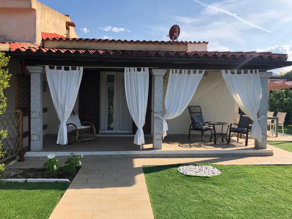 a patio with white curtains and a table and chairs at Ca' Viscomi in San Teodoro