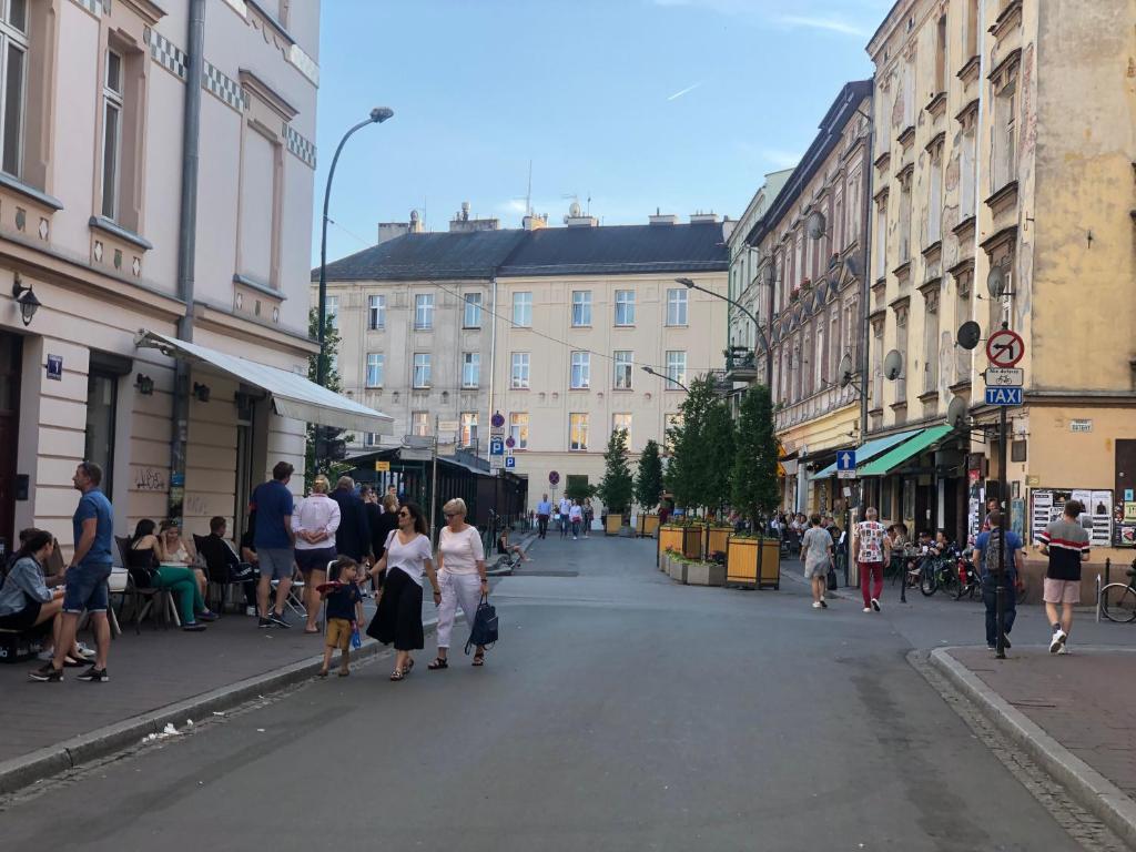 Urban street scene with pedestrians, sidewalk cafes, outdoor seating and historic multi-story buildings.