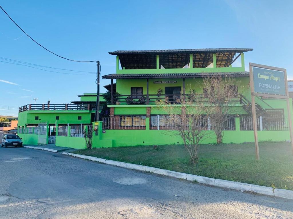un bâtiment vert avec un panneau devant lui dans l'établissement Pousada Campo Alegre, à Itatiaia