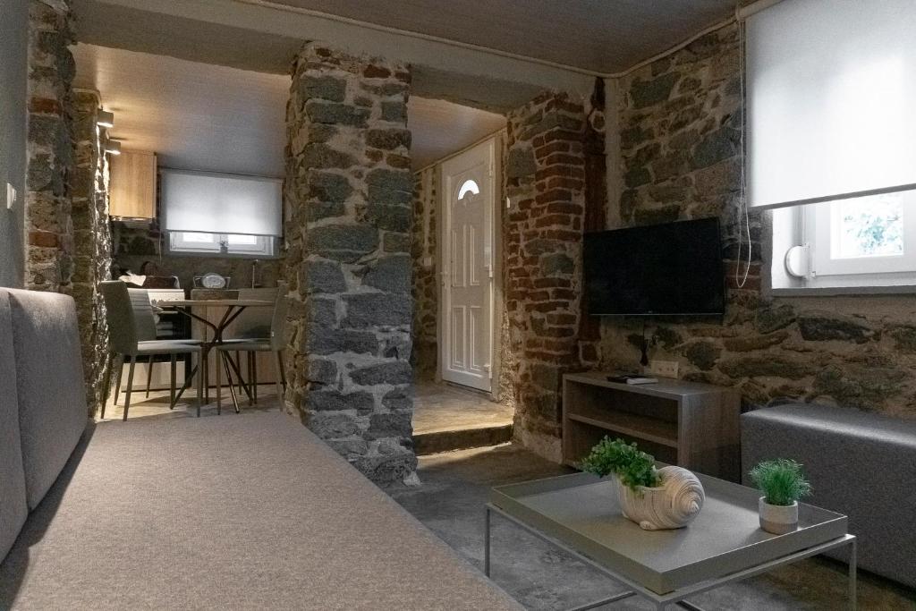 een woonkamer met stenen muren en een bank en een tv bij PETRA'S HOUSE in Kavala