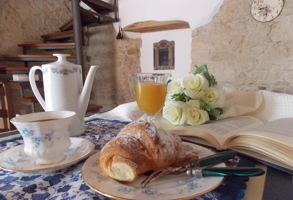 a table with a cup of tea and a croissant and a book at Casa Vacanze "Un sogno nel Blu'" in Baunei