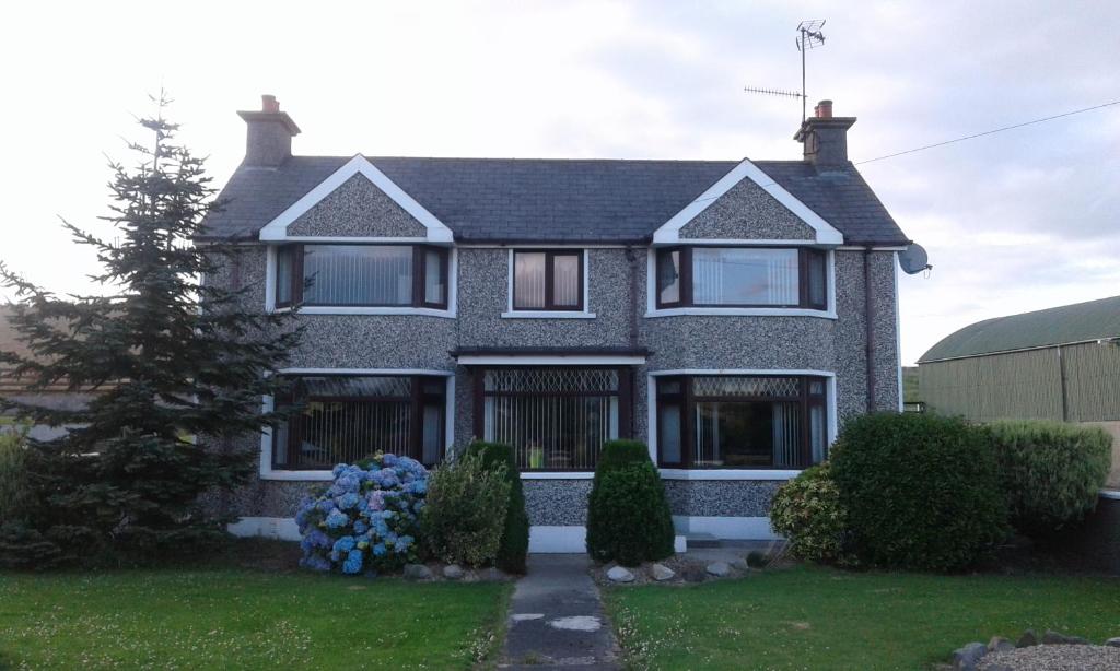 uma casa com flores azuis no jardim da frente em The Mournes view Farmhouse em Newcastle