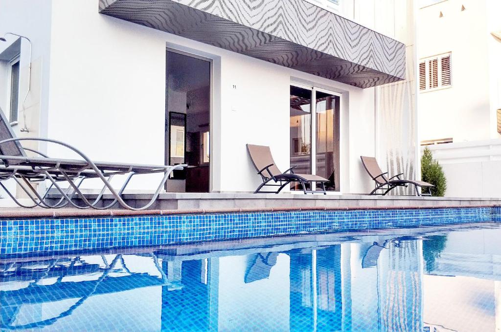 - une piscine avec des chaises à côté d'une maison dans l'établissement Nissini Nero, 3 bedroom villa with private pool, 5 min to the beach, à Ayia Napa